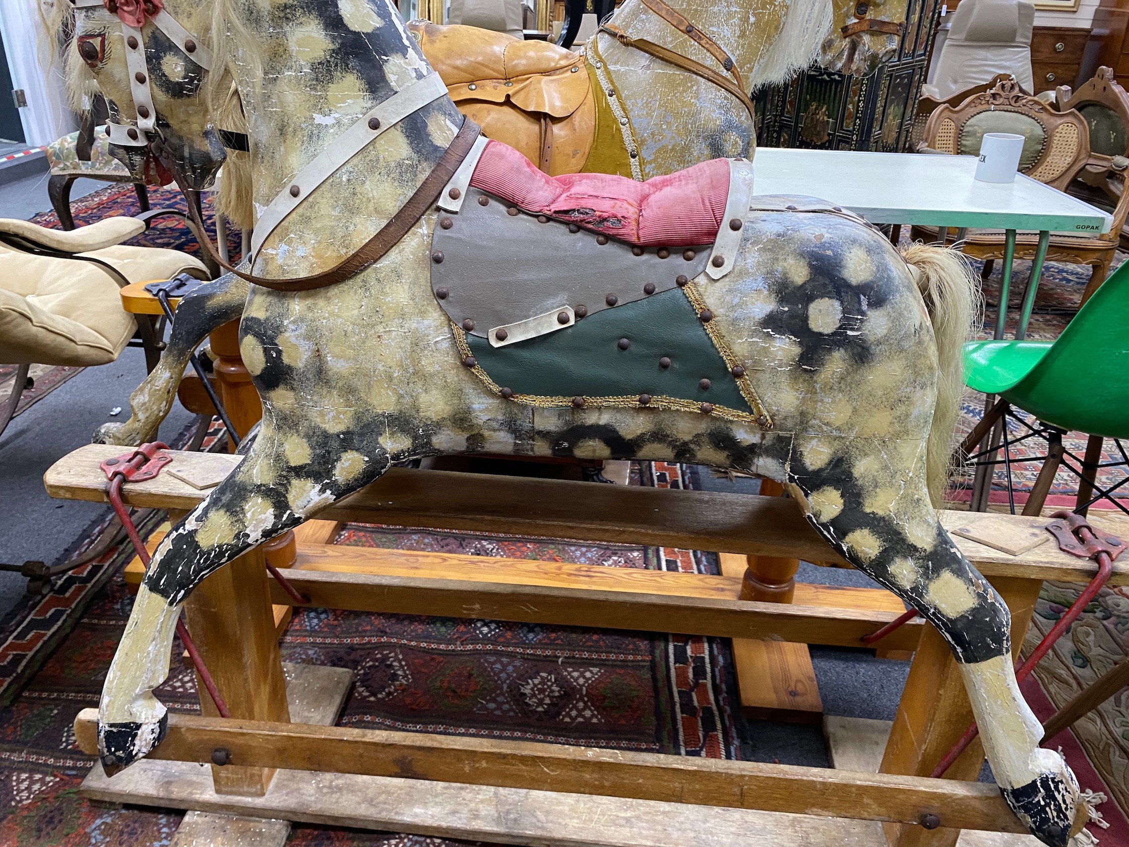 An early 20th century Ayres type carved wood and dappled rocking horse on safety frame, length 138cm, height 116cm